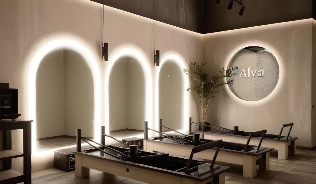Alva Pilates studio with lit arch mirrors, reformers, and warm boutique lighting